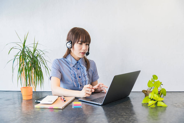 Asian female business person communicating online using laptop and internet - 写真・画像