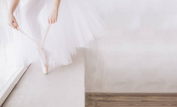 Ballet dancers feet on studio floor. Teenage dancer puts on ballet pointe shoes. Elegance and balance concept top horizontal view copyspace. - Foto, afbeelding