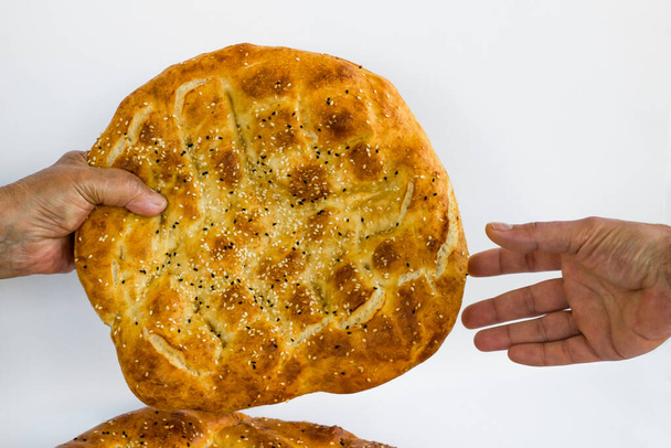 Two hands without gloves give ramadan bread to each other on white background. - Foto, Imagem