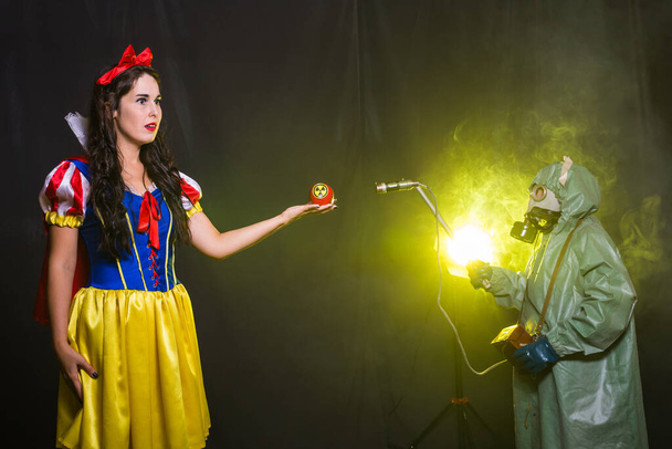 Femme portant une robe de conte de fées tenant une pomme avec un symbole de rayonnement. Notion de problèmes environnementaux, catastrophe radioactive comme danger pour la nature
. - Photo, image