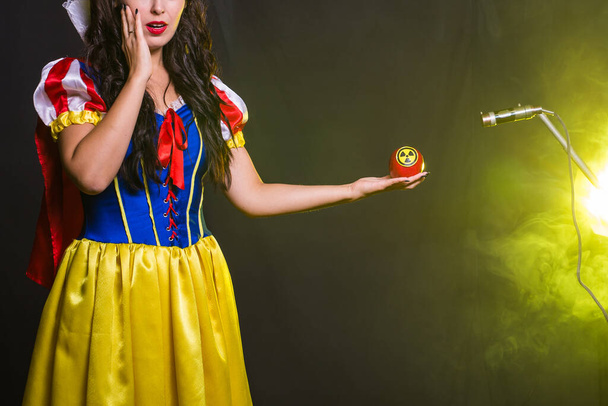Mesure du danger, du nucléaire et du rayonnement - La jeune fille tient une pomme avec un symbole de danger de rayonnement
. - Photo, image