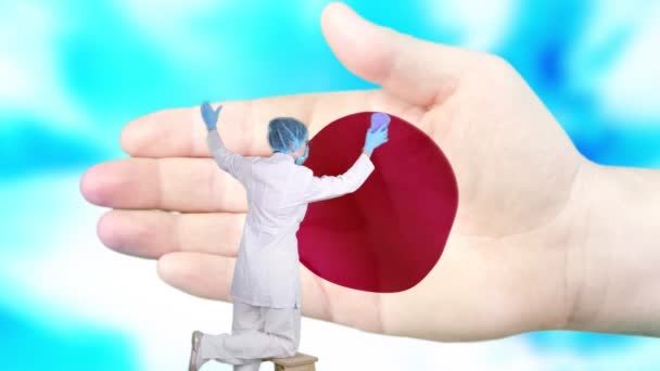 Nurse in medical mask and gloves washes large hand, painted in colors of Japan flag. State care for nation health. Wash your hands concept. Viruses protection. Diseases prevention. - Footage, Video