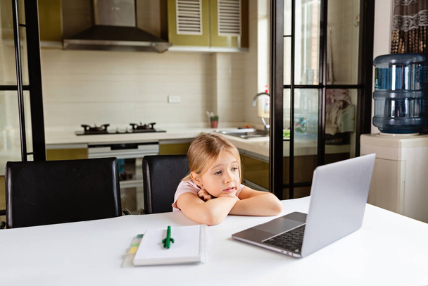 Pretty schoolgirl studying homework during her online lesson at home, social distance during quarantine covid-19, self-isolation, online education concept, home schooler. Workplace in living room - Fotoğraf, Görsel