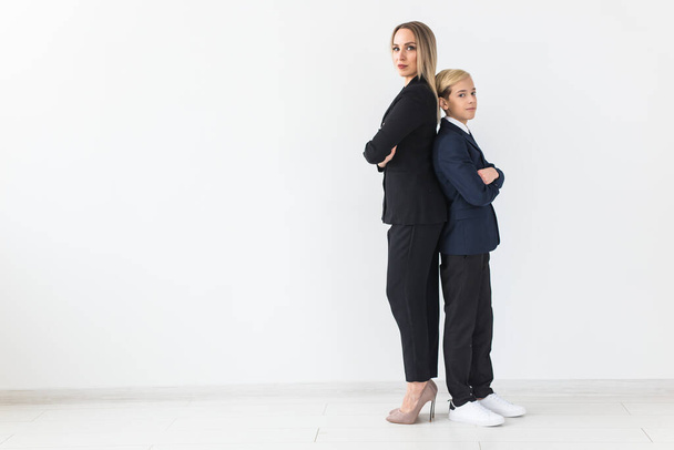 Teenager and single parent - Young mother and son standing together, back to back on white background with copy space. - Foto, Imagen