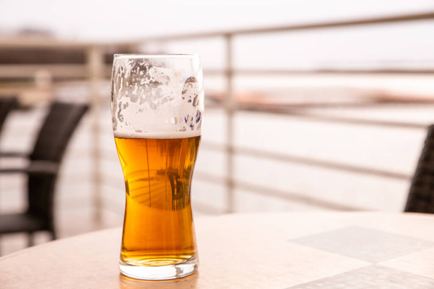 bázis egy pohár hideg sör áll az asztalon egy nyári kávézó fénymásoló hely - Fotó, kép