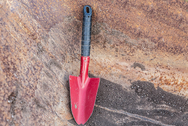 cuchara de hierro y rojo para trabajar en el jardín sobre un fondo marrón oscuro
 - Foto, Imagen