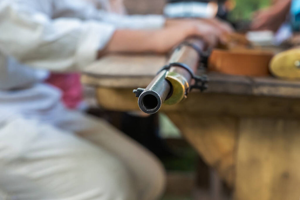 oud wapen, lange loop vuurwapens hoek op een zwart ijzeren vat - Foto, afbeelding