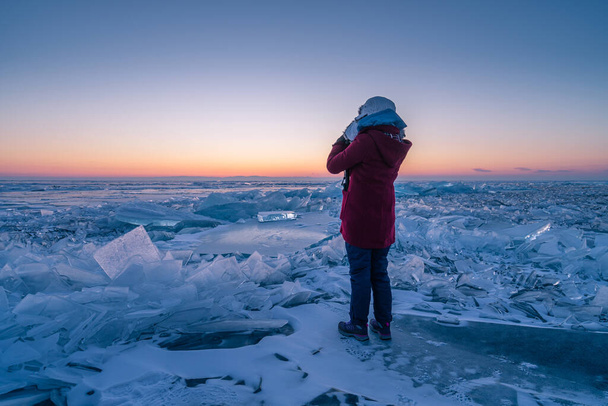 A traveller standing on ice in Baikal frozen lake in winter season at sunrise, Uzury bay, Siberia, Russia, Asia - Fotoğraf, Görsel