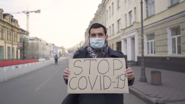 Trage beweging.Man met medisch masker protesteren met poster op straat. Woordpandemie - Video