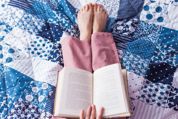 Primer plano de la mujer lleva pijama y relajarse en casa y leer un libro. Quédate en casa. Concepto de coronavirus pandémico de cuarentena
. - Foto, Imagen