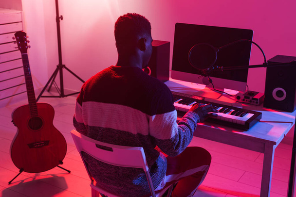 Επαγγελματική αφρικάνικη αμερικανική μουσικός ηχογράφησης synthesizer σε ψηφιακό στούντιο στο σπίτι, Μουσική έννοια της τεχνολογίας παραγωγής. - Φωτογραφία, εικόνα