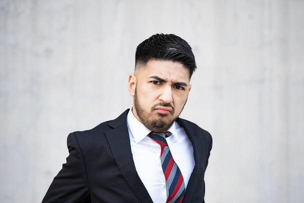 Mixed race young businessman with beard in suit screaming in despair - Фото, изображение