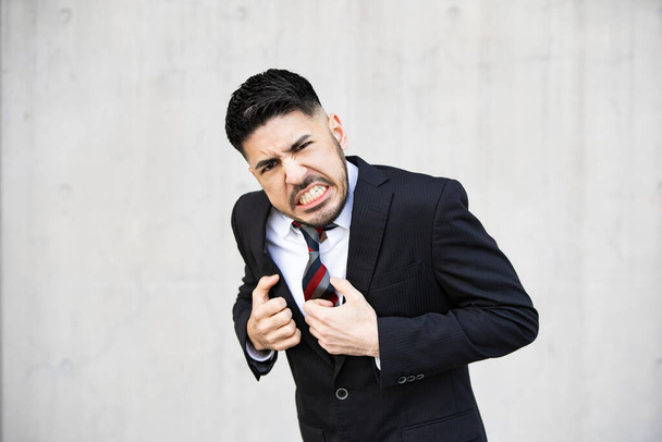 Mixed race young businessman with beard in suit screaming in despair - Photo, Image