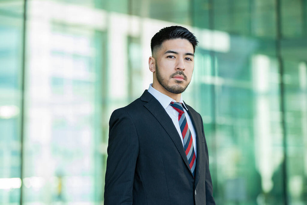 Gemischte Rasse junger Geschäftsmann mit Bart im Anzug steht draußen - Foto, Bild