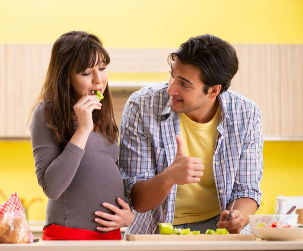 Homem e mulher grávida preparando salada na cozinha - Foto, Imagem