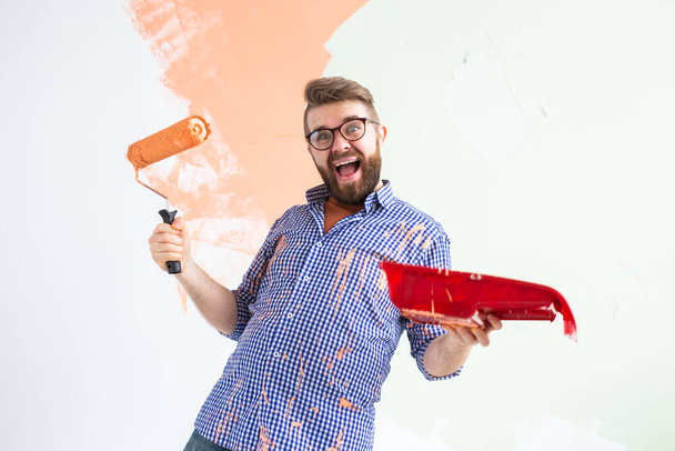 Un hombre gracioso pintando las paredes de un nuevo hogar. Concepto de renovación, reparación y redecoración
. - Foto, Imagen