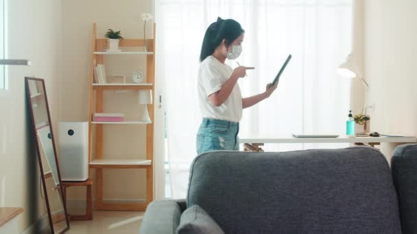 Asian business woman wearing mask using tablet working call video conference with customer in living room from home when social distancing stay at home and self quarantine time, coronavirus concept. - Metraje, vídeo