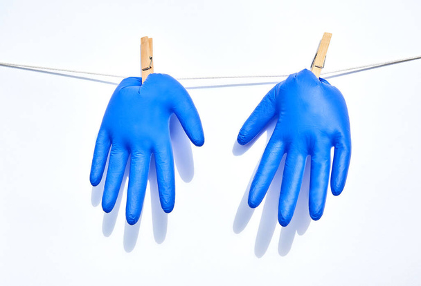 Blue medical gloves hang on cord, attached with pins. - Foto, Imagem