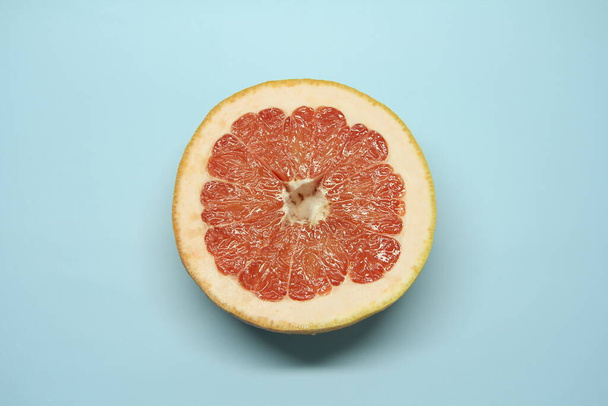 Half a juicy red grapefruit on a blue background. Place for text and design - Fotó, kép