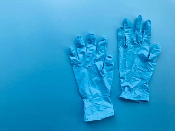 ein Paar blaue Medizinhandschuhe auf schlichtem, leeren blauen Hintergrund mit Kopierraum auf der linken Seite des Rahmens - Foto, Bild