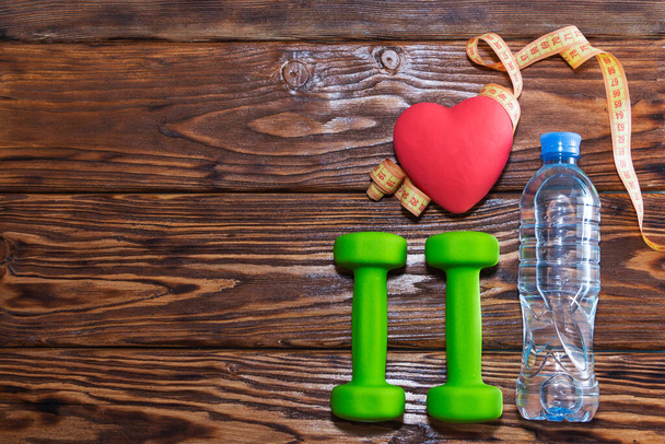 Manubri e un cuore rosso su uno sfondo di legno. Il concetto di uno stile di vita sano - Foto, immagini