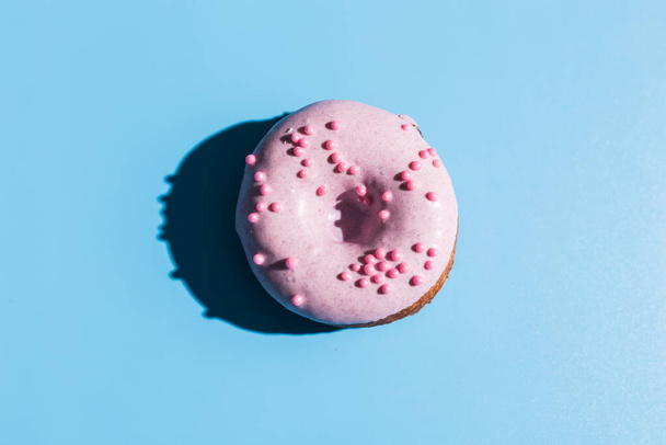 Trendy sunlight. Doughnut on bright light blue turquoise background. Minimal summer concept. Pop art style. Pink donut. - Photo, Image