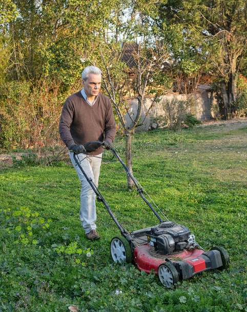Mann mit Rasenmäher im Frühling im Garten - Foto, Bild