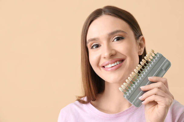 Schöne junge Frau mit Zähnen Farbproben auf beigem Hintergrund - Foto, Bild
