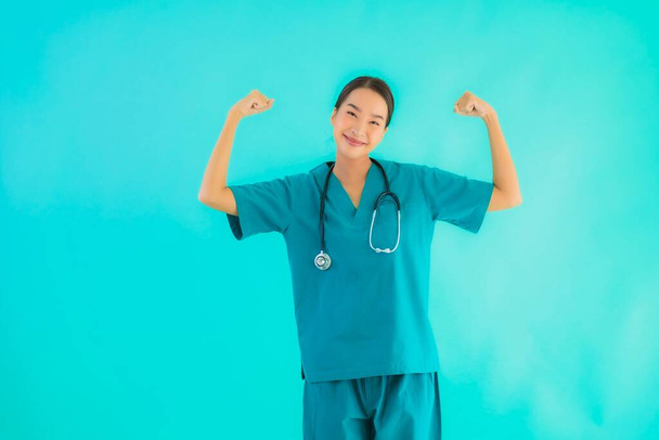 Portrait belle jeune asiatique médecin femme sourire avec beaucoup d'action sur fond bleu isolé
 - Photo, image