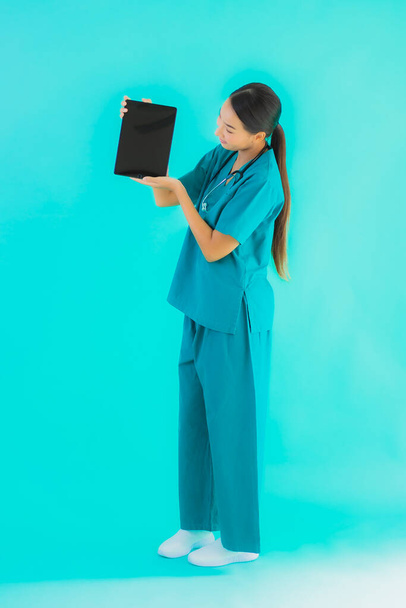 retrato hermosa joven asiático médico mujer uso inteligente tableta dispositivo en azul aislado fondo
 - Foto, imagen