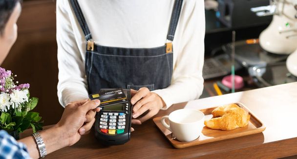 Asian customer using contact-less credit card nfs technology pay to barista at cafe bar. Contact-less payment preventing from corona-virus covid-19 Spreading and infection, Panoramic web banner crop. - Fotó, kép