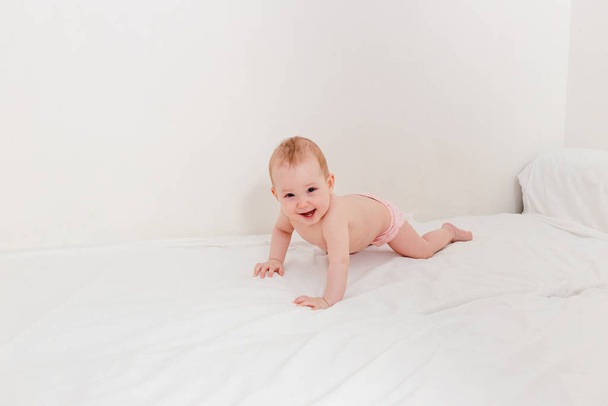 smiling baby girl in panty crawls on the bed - Фото, зображення