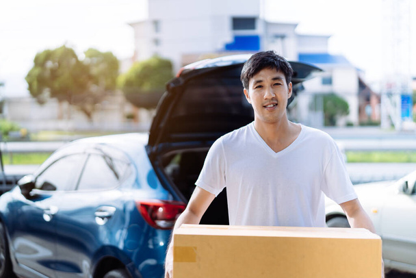 Delivery man carrying cardboard box for sending to receiver customer by transportation system hatchback car, Business product service for convenience of customer while the person is working at home. - Foto, afbeelding