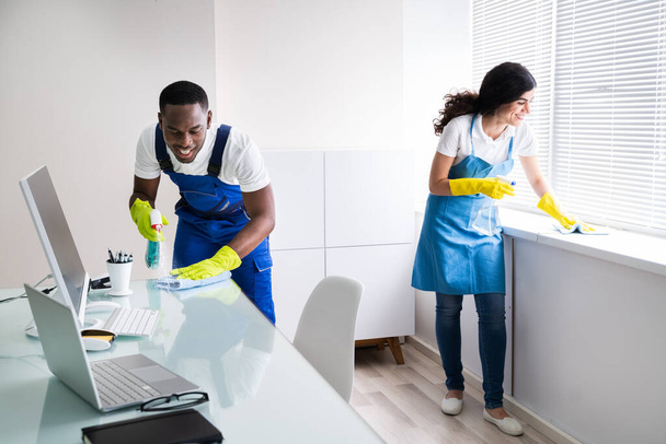 Young Male And Female Cleaners Cleaning Office - Foto, immagini