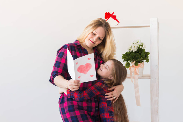 Happy mothers day. Child daughter congratulates mom and gives her postcard. Mum and kid girl smiling and hugging. Family holiday and motherhood. - Photo, image