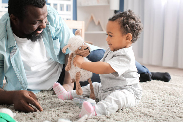 Afroamerikaner spielt zu Hause mit seinem süßen Baby - Foto, Bild