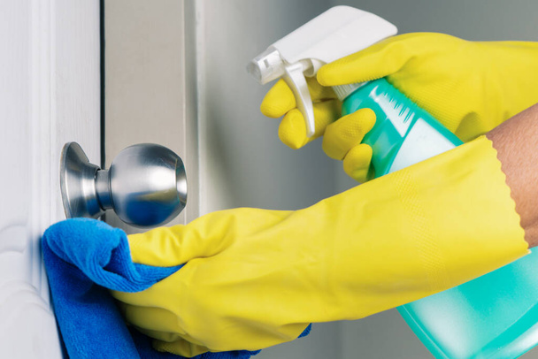 Cleaning door knob with alcohol spray for Covid-19 Coronavirus prevention - Photo, Image