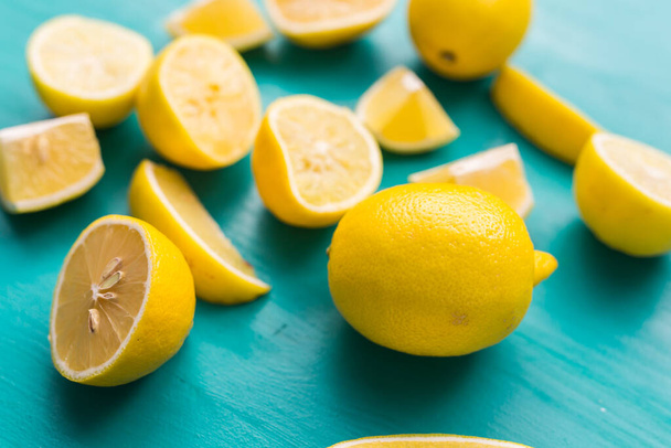 Čerstvě nakrájené půlky a celé citrony na rustikální akvamarínové barevné desky. Léto, vitamíny a svěžest koncept. - Fotografie, Obrázek