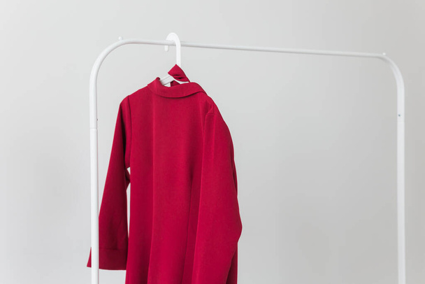 Rode jurk aan hanger op witte kamer. Mode-, verkoop- en winkelconcept. - Foto, afbeelding