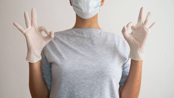 外科用マスクとラテックス手袋を持つ女性は、 OKシンボルを与えます. - 写真・画像
