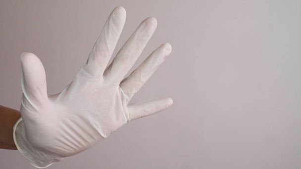 Stopping the disease. Prevention of viruses. Hand in white sterile latex surgical glove gives a stop sign. Negative space. Copy space for text. - Photo, Image