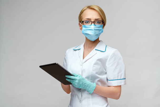 medical doctor nurse woman wearing protective mask and gloves - holding tablet pc - Foto, afbeelding