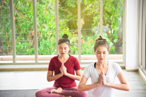 Dwie piękne azjatyckie kobiety, które ćwiczą, uprawiają jogę w pokoju, aby ćwiczyć swoje ćwiczenia ciała i kontrolę oddechu to popularne koncepcje utrzymania ciała.. - Zdjęcie, obraz