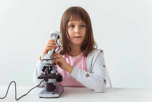 Schoolmeisje met behulp van microscoop in de wetenschap klasse. Technologieën, lessen en kinderconcept. - Foto, afbeelding