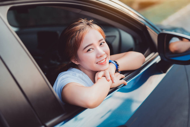 Asian woman smiling with Hatchback car travel driving road trip summer vacation in blue car at sunset,Girls happy traveling enjoy holidays and relaxation get the atmosphere and go to destination - Photo, Image