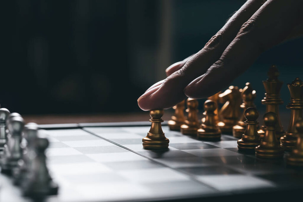Homem jogando estratégia de jogo de xadrez no tabuleiro de xadrez, plano de negócios conceito forte com fundo escuro
. - Foto, Imagem