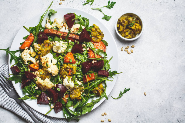 Baked sweet potato, cauliflower and beetroot salad with mustard dressing in a white plate, copy space. Healthy vegan food concept. - 写真・画像