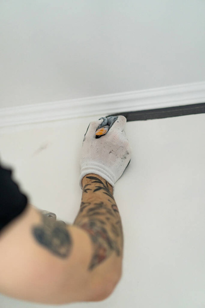 repairs. the man paints the walls with a roller, prepares for painting, repairs in the room. repaint the wall. - Foto, Imagen