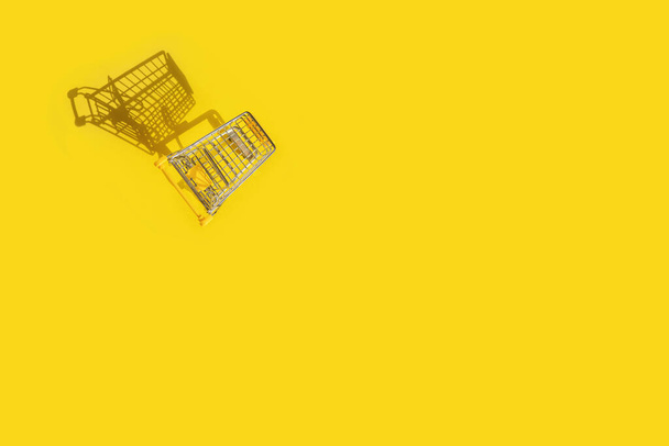Shopping cart on yellow background. - 写真・画像