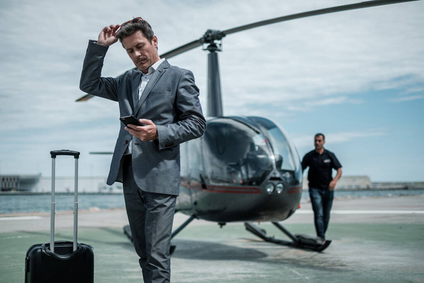 Homme d'affaires debout près d'un hélicoptère privé
 - Photo, image